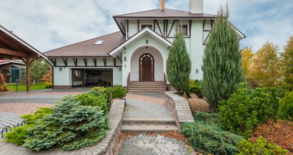 Elegant suburban house with decorative plants and paved driveway.