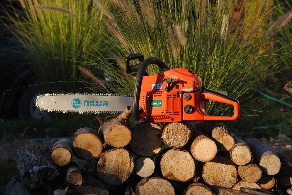 Orange chainsaw resting on a stack of cut logs
