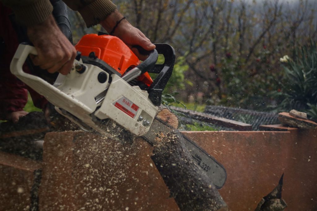 Worker cutting a tree limb into sections with a chainsaw