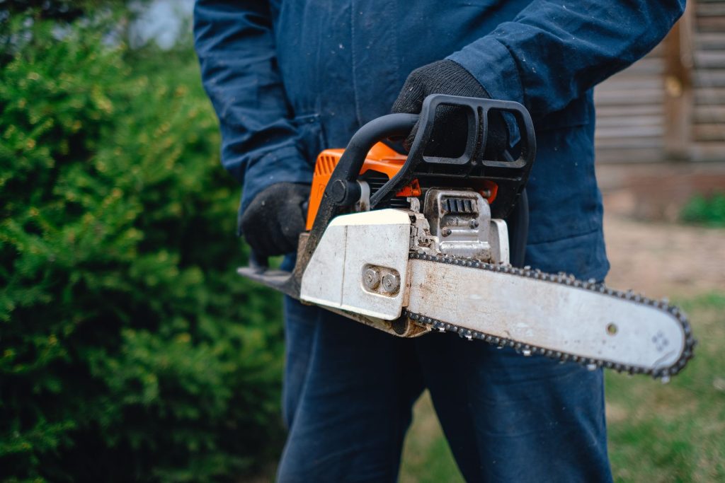 Worker in gloves holding a chainsaw
